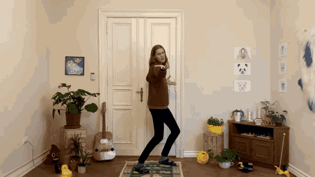 a woman is dancing in a room with a pink guitar on the floor