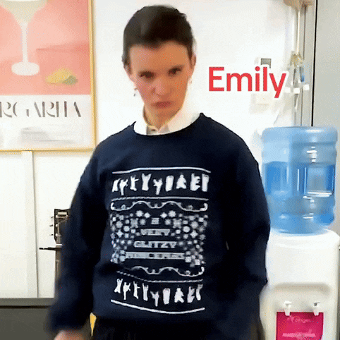 a woman wearing a sweater that says emily is standing in front of a water cooler