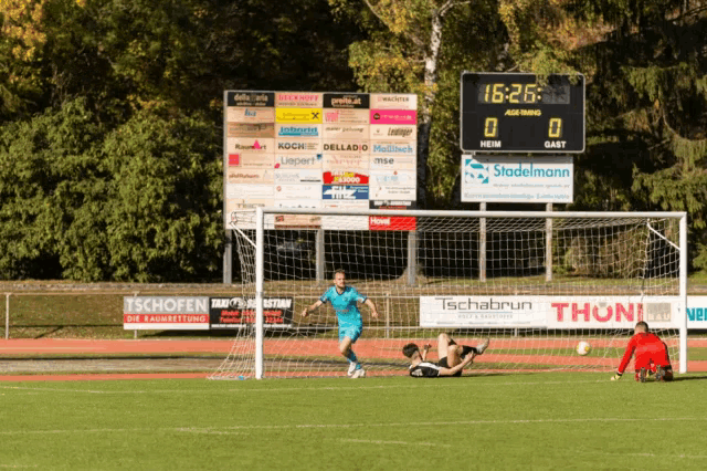 a soccer game is being played on a field with a scoreboard showing the score as 0 to 0