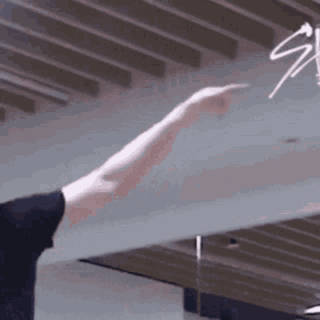 a person is pointing at something in the air while standing in front of a ceiling .