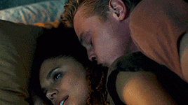 a man and a woman are laying on a bed with their eyes closed