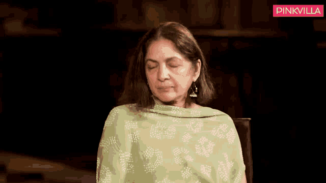 a woman in a green dress is sitting in a chair and smiling at the camera .