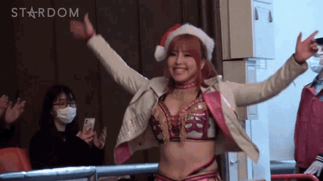 a woman wearing a santa hat is standing in front of a wall that says stardom on it