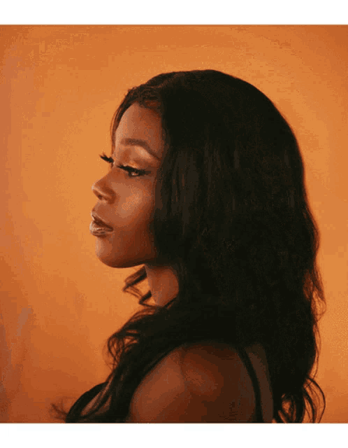 a woman 's face is shown in front of an orange backdrop