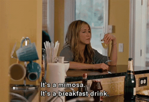 a woman sitting at a counter drinking a mimosa and breakfast drink