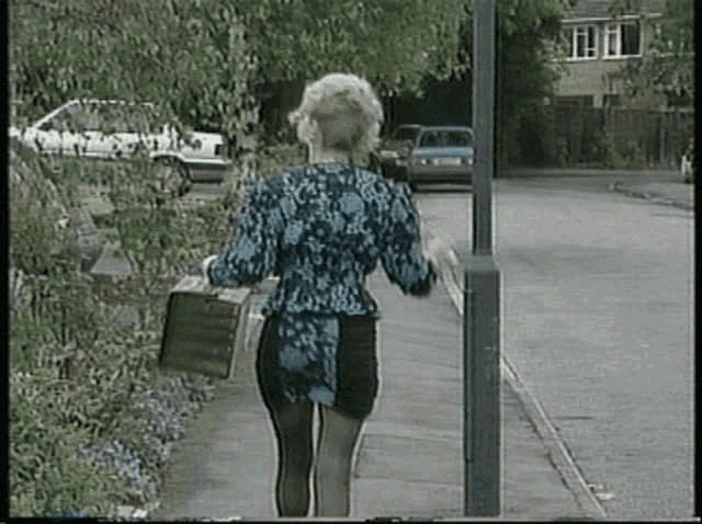 a woman is walking down a sidewalk with a briefcase in her hand