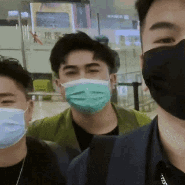 a man wearing a green face mask stands next to two other men