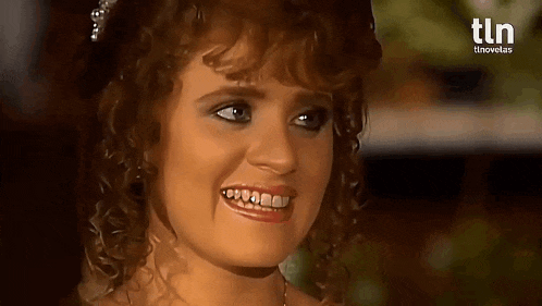 a woman with curly hair is smiling with a tln logo in the background .