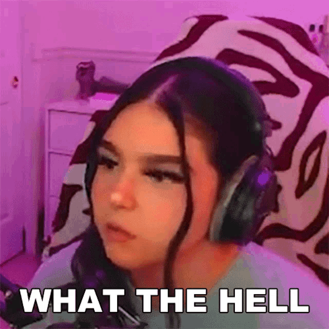 a woman wearing headphones is sitting in front of a microphone and saying what the hell .
