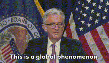 a man in a suit and tie is standing in front of an american flag and says this is a global phenomenon
