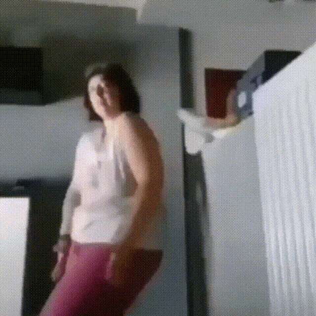 a woman is dancing in a room in front of a white wall .