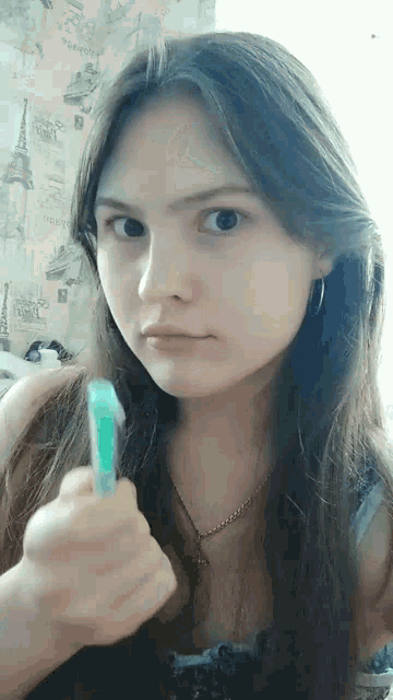 a young girl with long hair is holding a blue object in her hand .