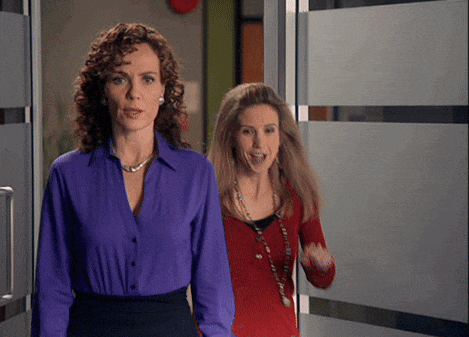a woman in a purple shirt stands next to another woman in a red sweater