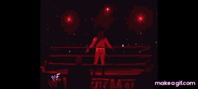 a wrestler is standing in the middle of a wrestling ring with flames coming out of it .