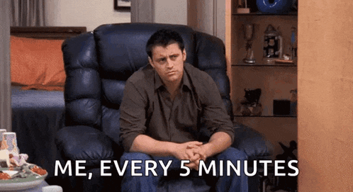 a man is sitting in a chair with his hands folded and the words `` me , every 5 minutes '' written on the screen .