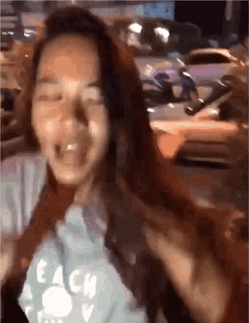 a woman wearing a t-shirt that says beach is standing in front of a busy street .