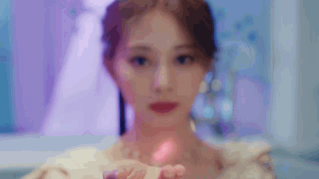 a close up of a woman 's face with a purple background holding a pink object in her hand .