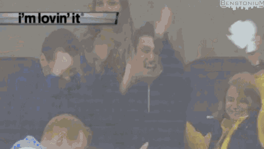 a group of people are watching a hockey game and the score is 1 to 0