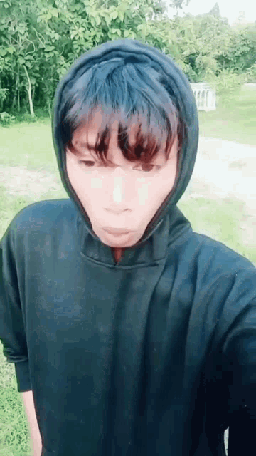 a young man wearing a black hoodie takes a picture of himself