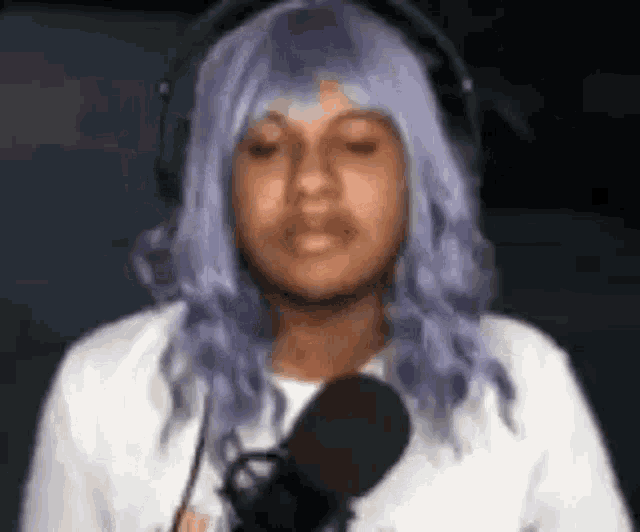 a man with purple hair is wearing headphones and a microphone .