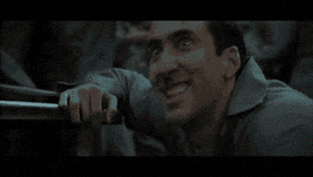 a man is smiling while holding a railing in a dark room