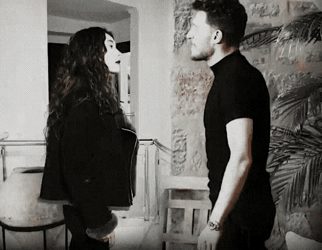 a man and a woman are standing next to each other and looking at each other