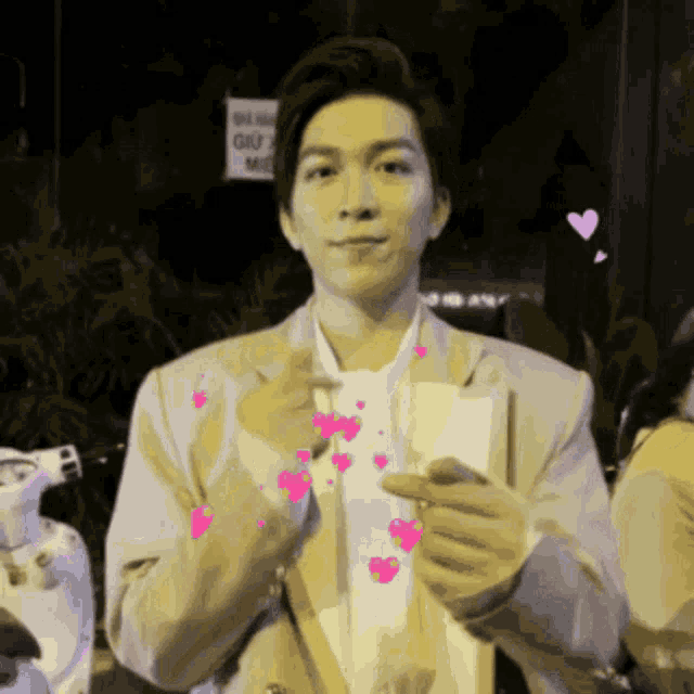 a man giving a thumbs up with pink hearts around him