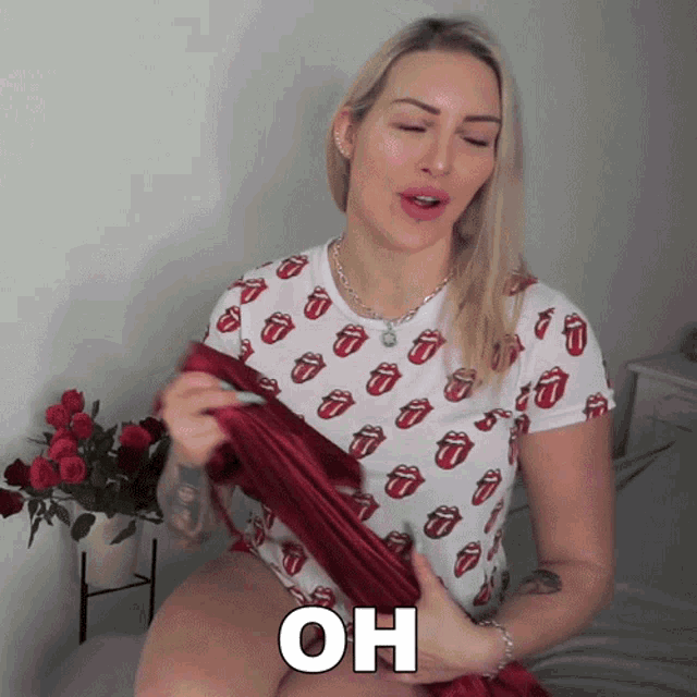 a woman wearing a rolling stones shirt is holding a red cloth and says oh