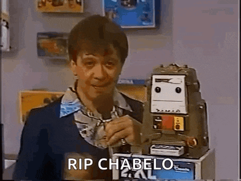 a man is holding a microphone in front of a robot and says `` rip chabelo '' .