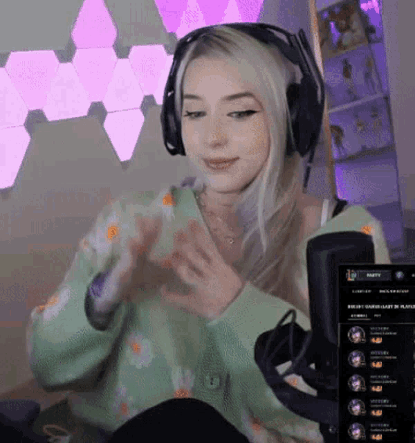 a woman wearing headphones and a green sweater is playing a game