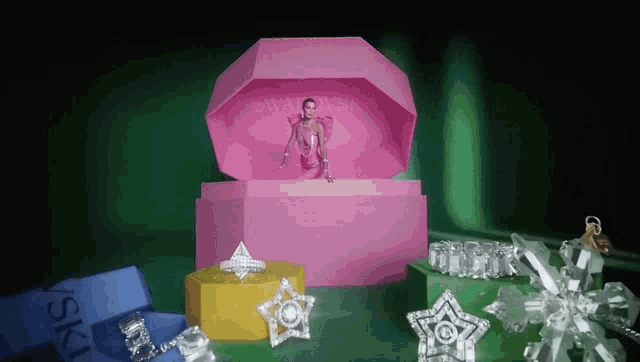 a woman in a pink dress is standing inside of a pink box that says swarovski