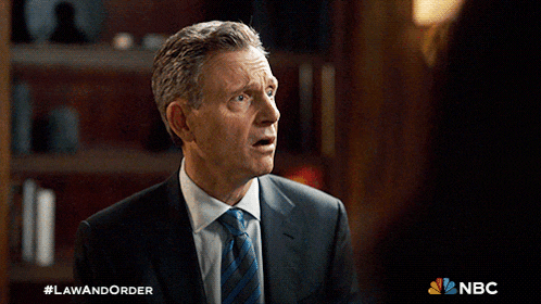 a man in a suit and tie is standing in front of a sign that says law and order
