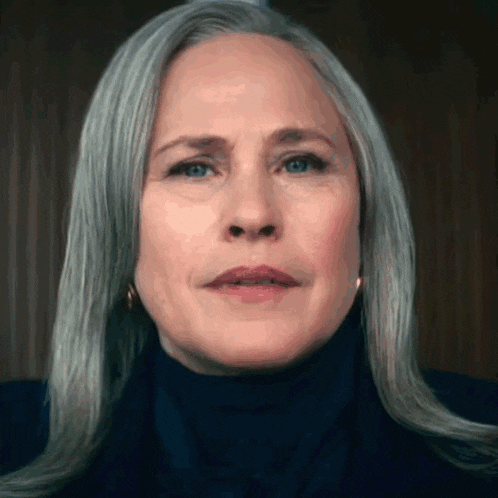 a close up of a woman 's face with gray hair and a black turtleneck .