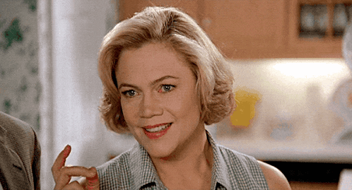 a woman in a plaid shirt is smiling and pointing her finger