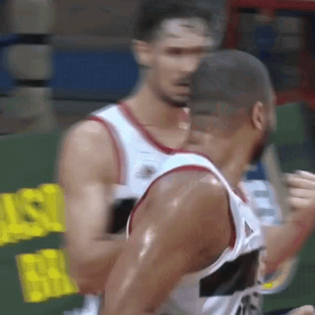 a blurry picture of two basketball players in front of a sign that says ' nsl ' on it