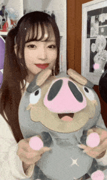 a girl holding a stuffed animal with a pig 's face on it