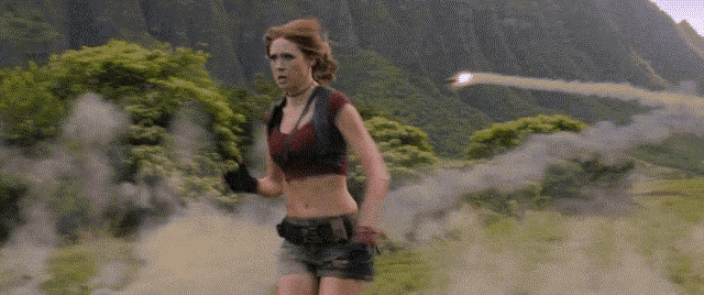 a woman in a crop top is running through a field holding a gun .