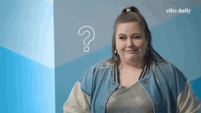 a woman stands in front of a blue wall with a question mark above her head