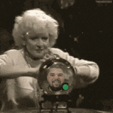 a woman is holding a crystal ball with a picture of a man inside of it