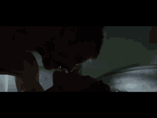 a man is kissing a woman on the neck in a dark room