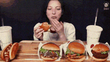 a woman is eating a hamburger and a hot dog at a table .