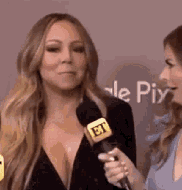 a woman is talking into a microphone while another woman stands behind her .