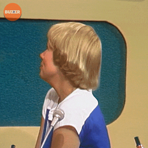 a woman sitting in front of a microphone with buzzr written on the bottom right