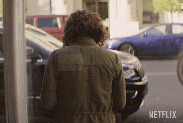 a woman in a green jacket is standing in front of a netflix logo