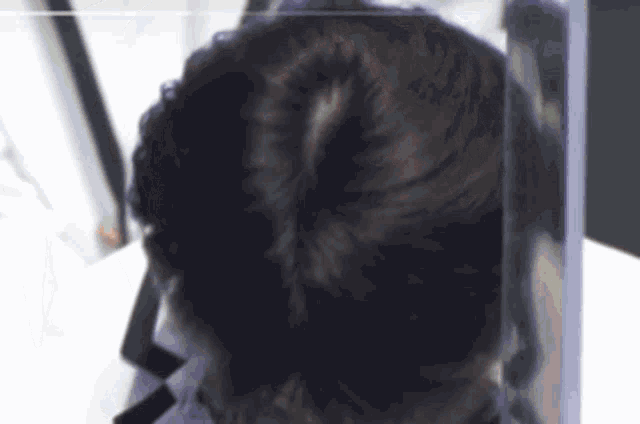 a close up of a person 's head with a bun in a glass container .