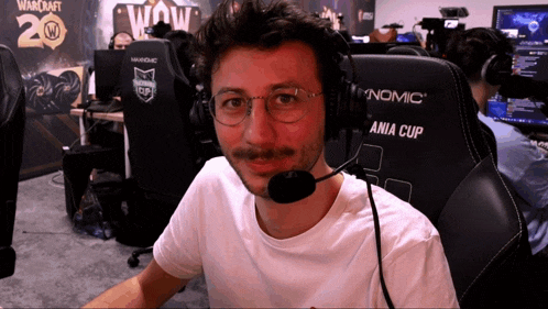 a man wearing glasses and headphones is sitting in front of a chair that says ania cup