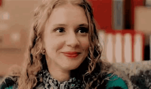 a close up of a woman with curly hair smiling while sitting on a couch .