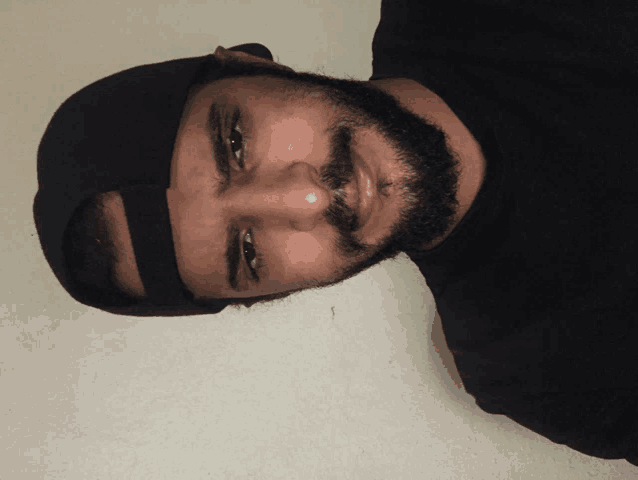 a man with a beard wearing a black hat and black shirt