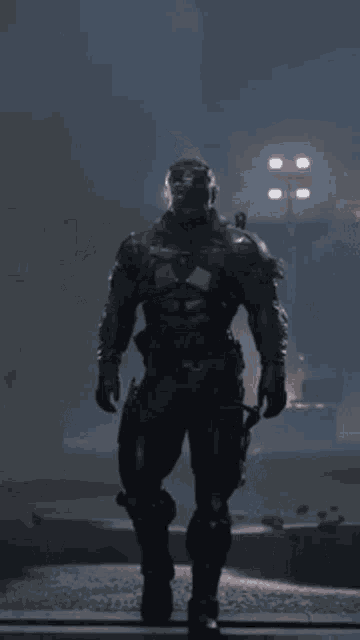 a man in a futuristic suit with a helmet on stands in the dark