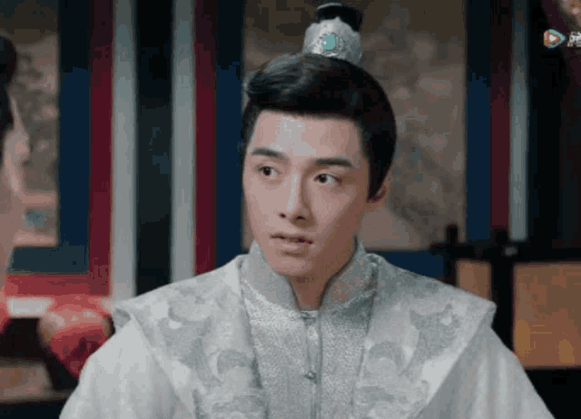 a man with a crown on his head is wearing a white robe